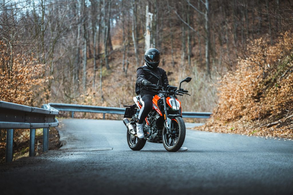 Motard sur une ktm arrêté au milieu de la route un pied au sol et qui regarde l'objectif