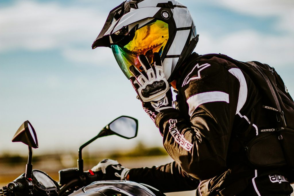Motard casqué sur sa moto, qui met la main sur son casque