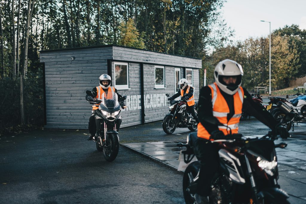 3 motards en gilet orange, en apprentissage